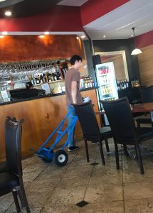 delivery man walking with trolley in restaurant